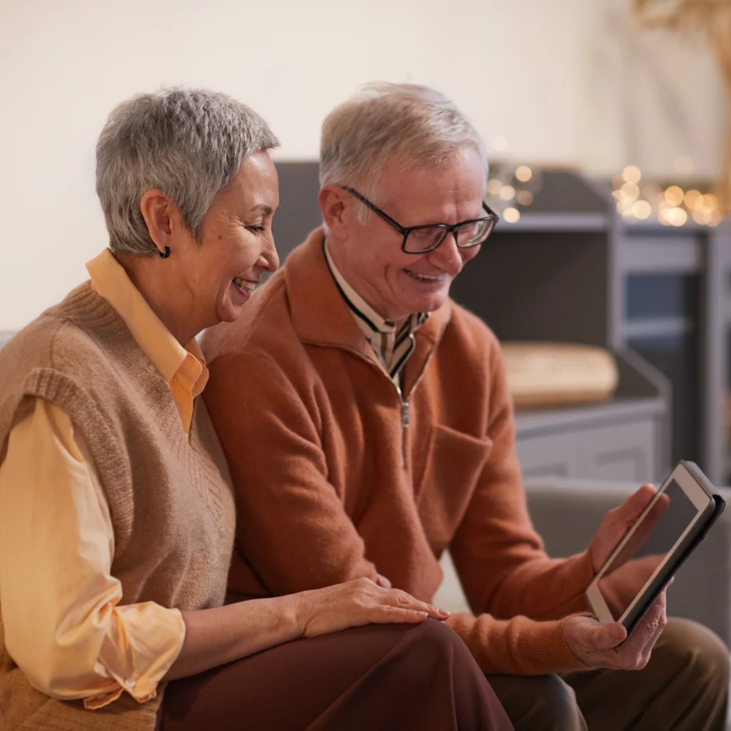 Couple souriant regardant leur tablette.